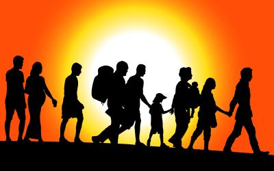 Silhouette of people walking in a line against an orange sky and bright sun. 