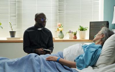 Pastor speaking with woman in hospital bed