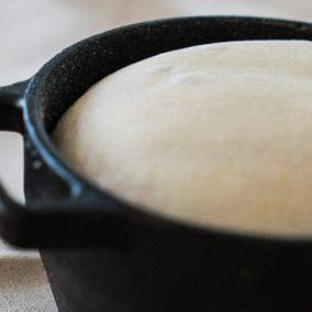 Bread being baked in a cast iron pot.