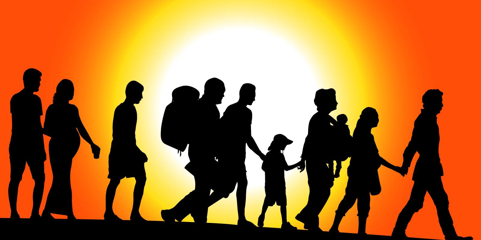 Silhouette of people walking in a line against an orange sky and bright sun. 